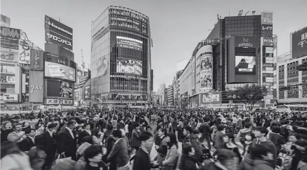 Busy pedestrian crossing in a bustling city center with illuminated billboards for B2 First (FCE) speaking test practice.